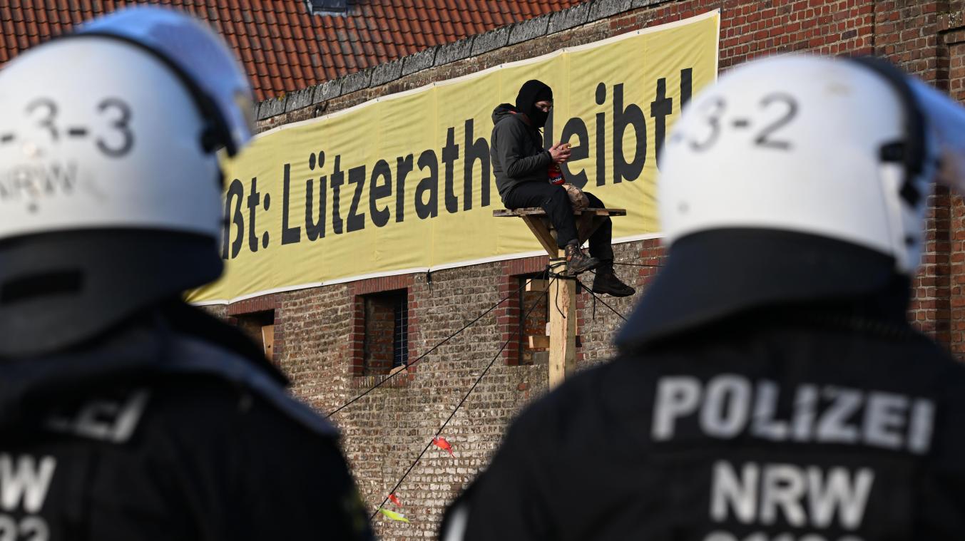 <p>Ein Demonstrant sitzt bei der Räumung des Dorfes Lützerath auf einer Holzkonstruktion vor einem Plakat mit dem Slogan „Lützerath bleibt!“.</p>