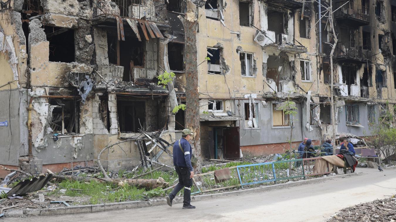 <p>Ein Mann geht an einem zerstörten Wohnhaus in Mariupol vorbei.</p>